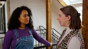 Op de foto staat presentator Ciana te praten met een vrouw in het trappenhuis van een gebouw.