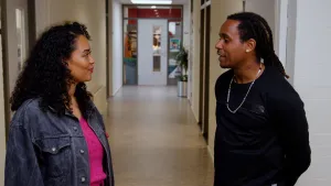 Een foto van presentator Ciana die met een man praat terwijl ze in de gang staan van een school.