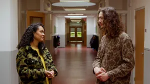 Een foto van presentator Ciana die met een man in de gang staat van een school.