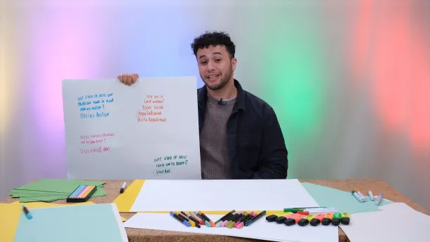 Een foto van meneer Khalil met in zijn hand een mindmap met vragen en antwoorden van een brainstorm sessie. Voor zich op tafel liggen vellen papier van verschillende kleuren en ook pennen, potloden en stiften van verschillende kleuren.