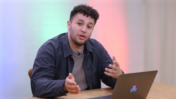 Een foto van meneer Khalil die achter een tafel zit. Voor meneer Khalil staat een laptop.