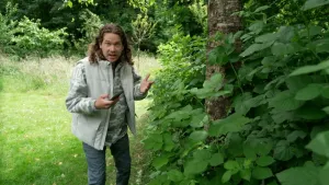 Een foto van presentator Pascal die buiten naast een boom met planten staat met een telefoon in zijn hand.