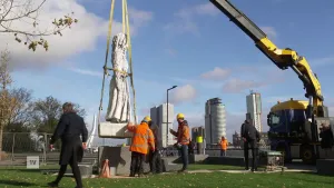 Een foto van mensen die met behulp van een kraan een standbeeld plaatsen.