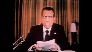 Een foto van oud president Nixon die een toespraak houdt terwijl hij naar de camera kijkt.