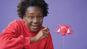 Een foto van Tirsa die naast een kleine plastic versie van de baarmoeder zit.