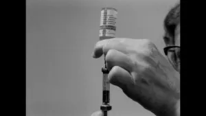 Een foto van een man die een spuit vasthoudt en die in een vaccin steekt.