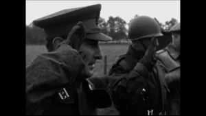Een foto in zwart-wit van soldaten die een soldatengroet brengen door hun hand aan hun hoofd te zetten.