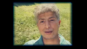 Een foto van het gezicht van een presentator die op een grasveld staat en veel ouder lijkt op de foto dan hij is. Dit komt doordat hij een 'ouder lijken' functie van een app op zijn mobiele telefoon gebruikt om de foto te nemen.