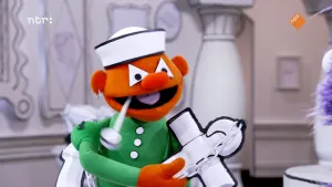 Een foto waarop een pop te zien is die een matrozenhoed opheeft, een pijp in zijn mond heeft en een anker in zijn hand heeft.  