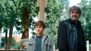 Foto van jongen Hein en een man die kijken naar de verte met bomen op de achtergrond.