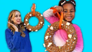 Foto van presentator Rosalie en meisje die allebei een eigen krans vasthouden, versierd met kruidnoten.