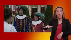 Foto van gebarentolk naast scherm met piet Hoofdpiet en Boekpiet voor het Grote Pietenhuis.