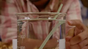 Foto van maatbeker met water met rietje erin, de bovenkant van het rietje komt op een andere plek uit het water dan het deel van het rietje dat onder water zit.