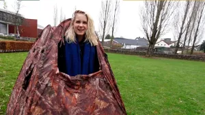 Op deze afbeelding is Janouk te zien. Ze komt uit een tent om op zoek te gaan naar de huismus. De tent staat in een grasveld.