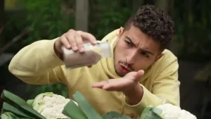 Op de afbeelding is de presentator te zien die een potje met fosfaat heeft. Fosfaat is hier verbeeld in poedervorm. Onder hem liggen verschillende groenten.