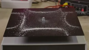 Foto van zwarte stalen plaat met witte zoutkorrels in een vierkant patroon met buigende lijnen.