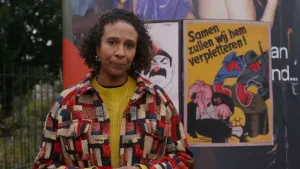 Astrid staat naast een zuil. Hierop hangen propaganda posters