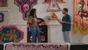 Een foto van presentator Nizar. Hij is in gesprek met kunstenares Hemaseh. Ze staan in een kamer met wandtapijten aan de muur en met een tapijt dat over een tafel ligt. Het zijn kleurrijke tapijten in allerlei vormen.