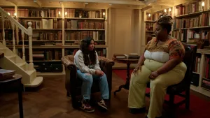 Foto van meisje in stoel naast plussizemodel in bibliotheek.