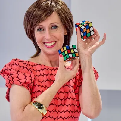 Foto van presentatrice Dorine Goudsmit met twee rubiks kubussen in het decor van Welkom in de geschiedenis