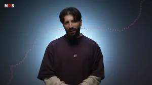 Een foto van presentator Devran. Hij staat in een studio en kijkt in de camera. Achter hem loopt een animatie van de grens tussen Noord- en Zuid-Korea, uitgebeeld door een stippellijn.