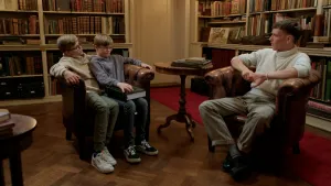 Foto van tweeling Pim en Thijs samen op een leren stoel, in gesprek met jonge klimaatactivist in een oude bibliotheek.