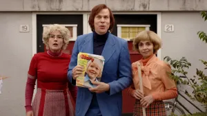 Foto van man met de eerste Story in zijn hand, met naast hem twee vrouwen gekleed in jaren 70-kleding.