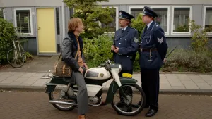 Foto van man op brommer die wordt aangehouden op straat door twee politieagenten.