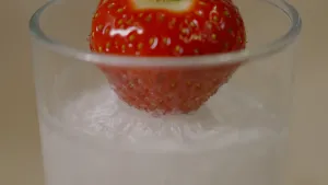 Foto van aardbei in een glas met bevroren vloeistof.