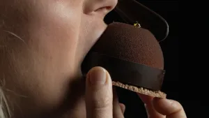 Een foto van de mond van presentatrice Janouk die in een chocoladetaartje bijt, van opzij gezien.