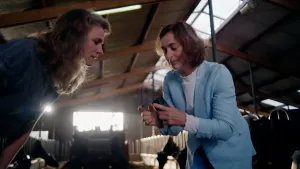 Foto van presentatrice Petra Grijzen samen met onderzoekster in koeienstal waar ze resultaten van een proefje bekijken.
