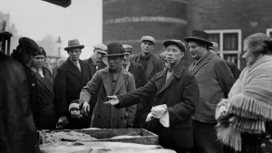 Zwart wit beeld van een aantal mannen met Chinees uiterlijk met hoeden op een markt.