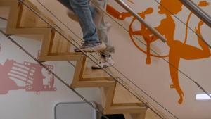 Foto van de zijkant van een houten trap waarop twee mensen naar boven rennen