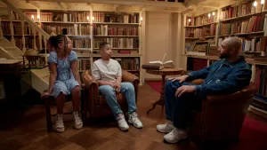 Foto van Edson da Graca tegenover twee kinderen die met hem praten in oude bibliotheek.