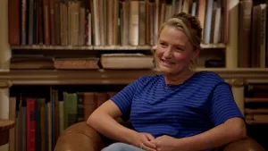 Foto van Krista Arriens, glimlachend voor oude boekenkast.