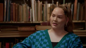 Foto van Nikkie de Jager voor een oude boekenkast.