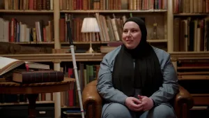 Foto van vrouw met hoofddoek en bindenstok in oude bibliotheek.