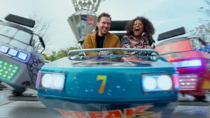 Een foto van presentatrice Quinty en een man in een kermisattractie, ze lachen.