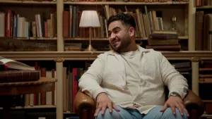 Foto van volkszanger Ammar lachend in een oude bibliotheek.