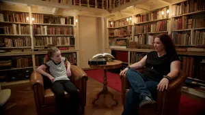 Foto van schrijfster Sanne Rooseboom in gesprek met een meisje in oude bibliotheek.