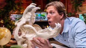 Een foto van Freek Vonk die vol bewondering naar de schedel van een Grizzlybeer in zijn handen heeft met scherpe lange witte tanden