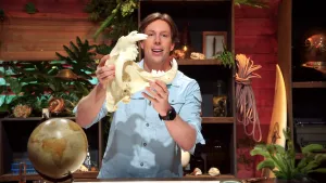 Een foto van Freek Vonk die glimlachend de schedel van een tijger met enorm scherpe tanden in zijn handen houdt.