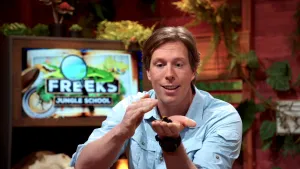 Een foto van Freek Vonk die een pijlgifkikker in zijn hand heeft en hem aait. 