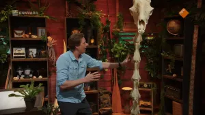 Freek Vonk die naast het skelet van een giraffe staat met een enorme nek.