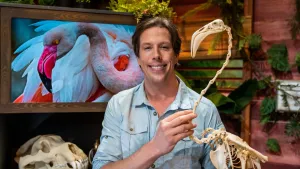Een foto van Freek Vonk die glimlachend het skelet van een flamingo vasthoudt.