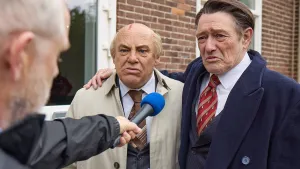 Foto van twee mannen, gekleed als Gorbatsjov en Reagan, die worden geinterviewd door man met microfoon.