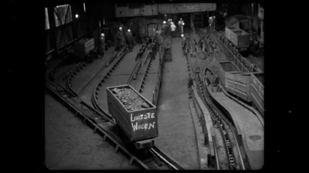 Een zwart-wit foto van een mijnkarretje met de tekst Laatste weken, het karretje staat op rails.