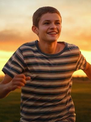 Jongen rent en kijkt blij. Achter hem rennen nog twee kinderen.