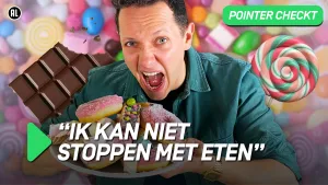 Een foto van een presentator die een hap wil nemen van allerlei ldonuts die hij op een bord heeft liggen, op de achtergrond zie je meer snoep zoals cholcolade en een lolly.