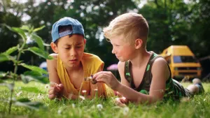 Een foto van twee kinderen die op hun buik in het gras liggen